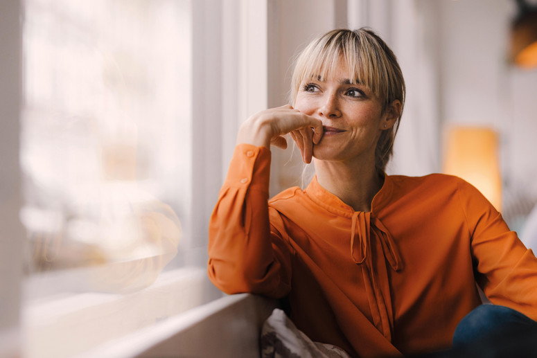Eine auf einer Couch sitzende Frau freut sich gedanklich über die von der SRH angebotenen Benefits im Karrierebereich.